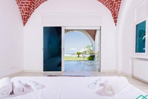 a bedroom with a white bed with a large window at Dar Barsha: Beach front white sand and happiness in Rafrāf