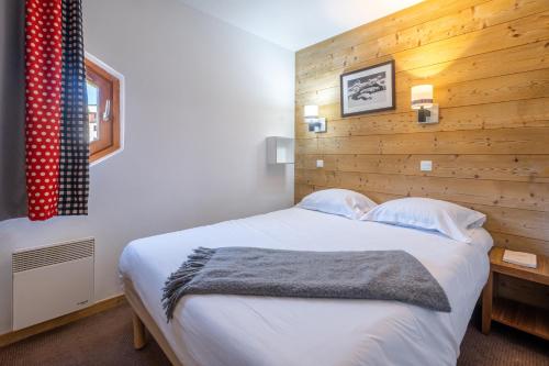 - une chambre avec un grand lit et un mur en bois dans l'établissement Résidence Pierre & Vacances Le Machu Pichu, à Val Thorens