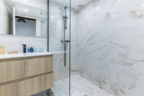 une salle de bain blanche avec une douche et un lavabo dans l'établissement Grands Boulevard 31 Appartement Cosy 3D, à Paris