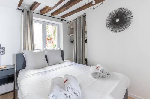 une chambre avec un lit blanc avec des serviettes dessus dans l'établissement Grands Boulevard 31 Appartement Cosy 3D, à Paris
