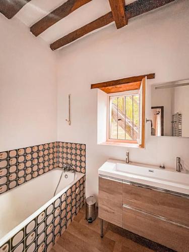 une salle de bain avec une baignoire et une fenêtre dans l'établissement Moulin de la Caluyére, à Ardenay-sur-Mérize
