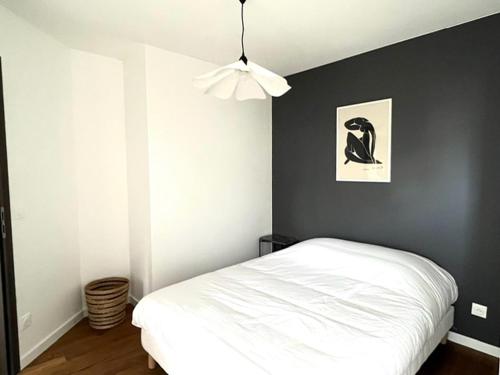 - une chambre avec un lit blanc et un mur noir dans l'établissement M25 Marquer joli T2 proche frontière, à Annemasse