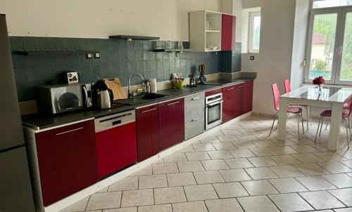 a kitchen with red cabinets and a table in it at Océane 100m2 dans demeure Bourgeoise in Beaucourt