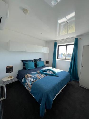 une chambre avec un lit avec des draps bleus et une fenêtre dans l'établissement JOIA Bassin d'Arcachon - LE ROOF 268, à La Teste-de-Buch