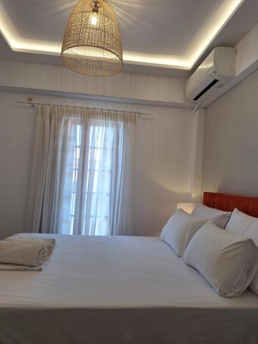 a bedroom with a large white bed with a window at Akrogiali in Agios Ioannis Pelio
