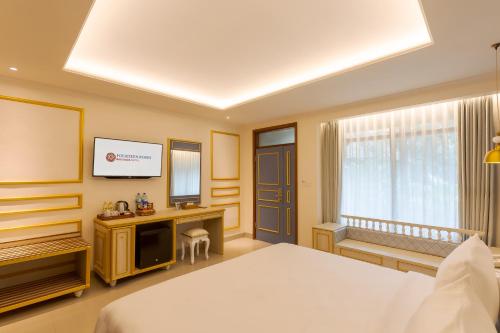 a hotel room with a bed and a television at Fourteen Roses Boutique Hotel, Kuta in Legian