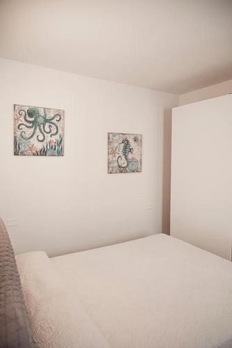 a white bedroom with two pictures on the wall at Lido Camaiore - Appartamento Il Pinolo in Camaiore
