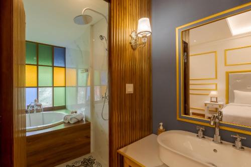 a bathroom with a tub and a sink and a mirror at Fourteen Roses Boutique Hotel, Kuta in Legian