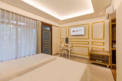 a bedroom with a white bed and a desk at Fourteen Roses Boutique Hotel, Kuta in Legian