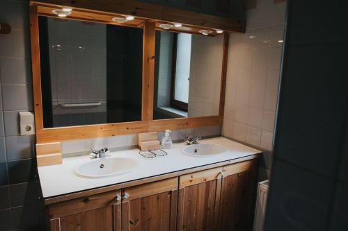 a bathroom with two sinks and a mirror at La barra'k Maison de vacances avec piscine in Waimes