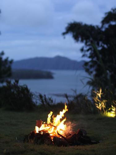 a fire pit in the grass with a view of the water at Calidas Hill in Kintamani