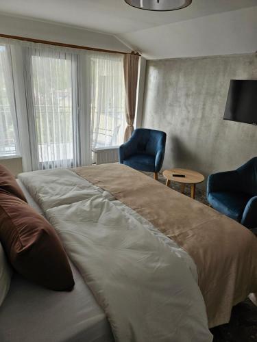 a bedroom with a large bed and two blue chairs at Hotel Sonnenhof in Bad Waldsee