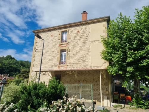une vieille maison en briques avec un arbre devant elle dans l'établissement La Maison Lourégo Tournesol, à Hauterives