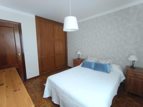 a bedroom with a white bed with blue pillows at Apartamento Ribadesella playa in Ribadesella
