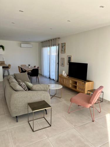 un salon avec un canapé et une télévision à écran plat dans l'établissement La Maison Louis - moderne & familiale, à Lapalme