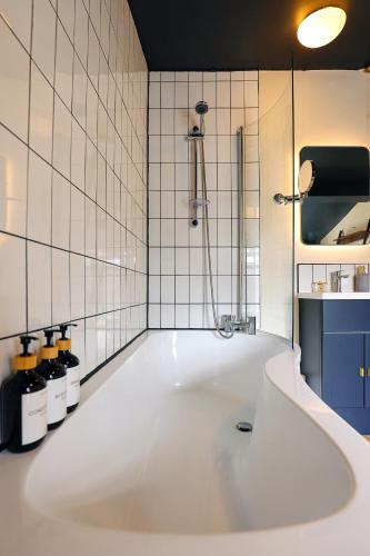 a white bath tub in a white tiled bathroom at Elmbank House in New Ferry