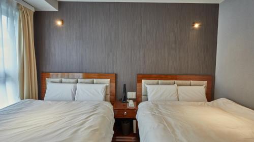 two beds in a hotel room with two bedsskirts at EZ HOTEL Kansai Airport Seaside in Izumi-Sano