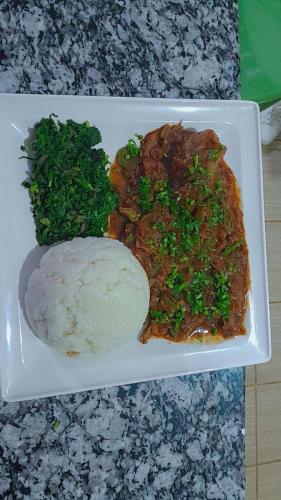 a plate of food with rice and broccoli on a table at COMFORT E SUITES in Nairobi