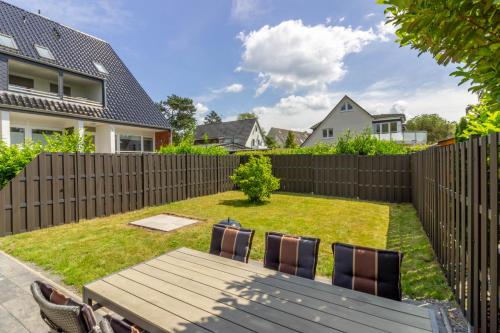 a backyard with a wooden fence and a wooden table and chairs at Küstennest in Timmendorfer Strand