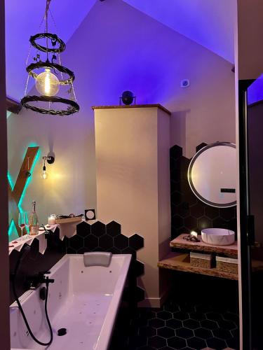 une salle de bain avec une baignoire, un lavabo et un miroir dans l'établissement Love Room 'Secret des Combles' Vosges, à Plombières-les-Bains