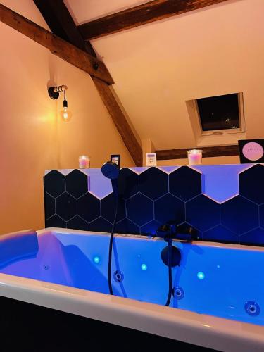 Cette chambre dispose d'une télévision et d'une grande baignoire bleue. dans l'établissement Love Room 'Secret des Combles' Vosges, à Plombières-les-Bains