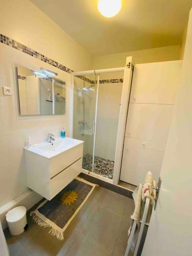 une salle de bain avec un lavabo blanc et une douche dans l'établissement T2 centre ville parking prive clim 300m plage, à La Grande Motte
