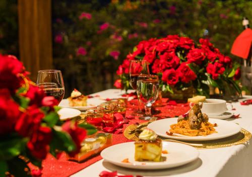 a table topped with plates of food and red roses at Villa Daun 3 Canggu by Premier Hospitality Asia in Dalung