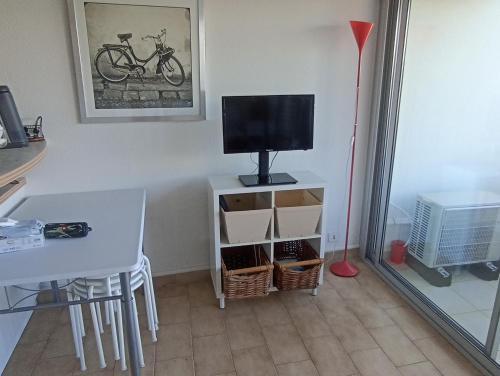 - un salon avec une télévision, une table et un bureau dans l'établissement Joli studio avec piscine à 200m de la plage parking privé, à La Grande Motte