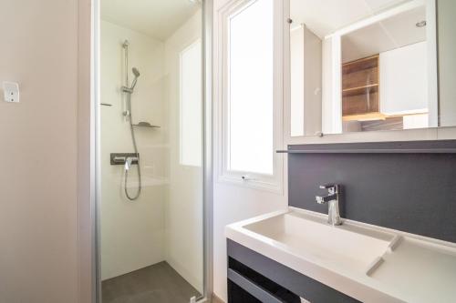une salle de bain avec un lavabo blanc et une douche dans l'établissement Charmant Mobil Home 6 personnes, à Vendres