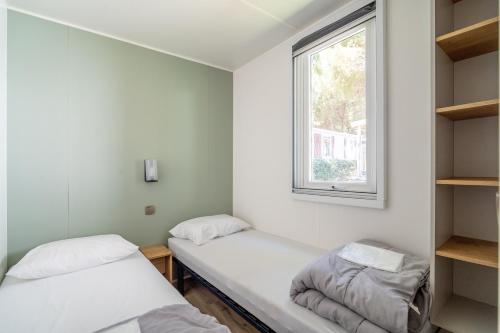 deux lits dans une chambre avec une fenêtre dans l'établissement Charmant Mobil Home 6 personnes, à Vendres