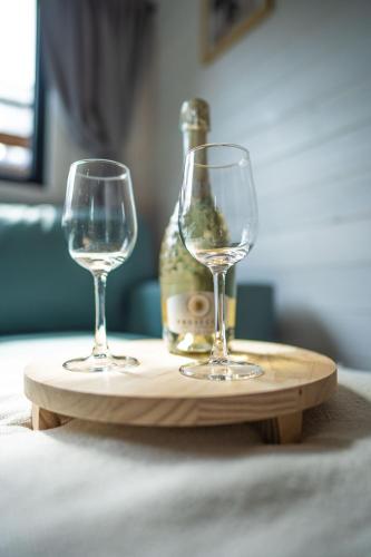 two wine glasses and a bottle on a wooden tray at Klimatyzowane Domki PREMIUM - Maszoperia Sun4Hel - Letnia Baza SnowShow na Półwyspie Helskim in Jastarnia