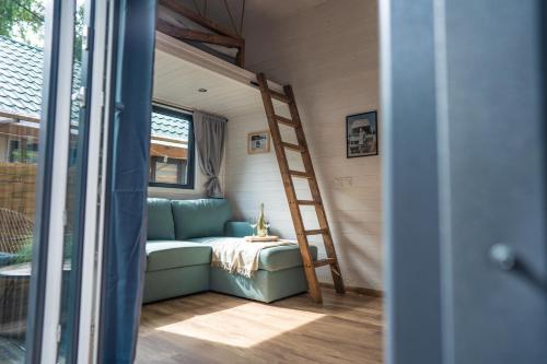 a couch in a tiny house with a ladder at Klimatyzowane Domki PREMIUM - Maszoperia Sun4Hel - Letnia Baza SnowShow na Półwyspie Helskim in Jastarnia