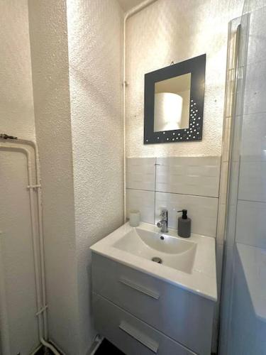 une salle de bain blanche avec un lavabo et un miroir dans l'établissement Casa Félix, à Perpignan