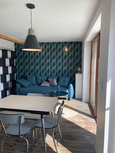 un salon avec un canapé bleu, une table et des chaises dans l'établissement Les deux oliviers, à Saint-Romans