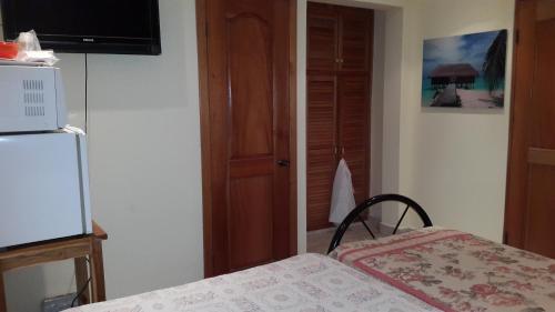 a room with a bed and a table and a television at Hostal Bocas Tropical Paradise in Bocas del Toro