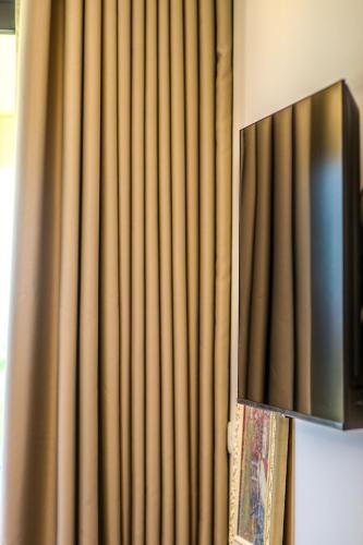a television hanging on a wall next to a curtain at Hercules Sea View in Himare