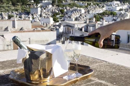 a person pouring a bottle of champagne and two glasses at Hotel Lanzillotta in Alberobello