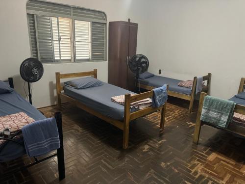 een kamer met 3 bedden en stoelen en een raam bij Pousada da Dindinha Cacia in Monte Alegre de Minas