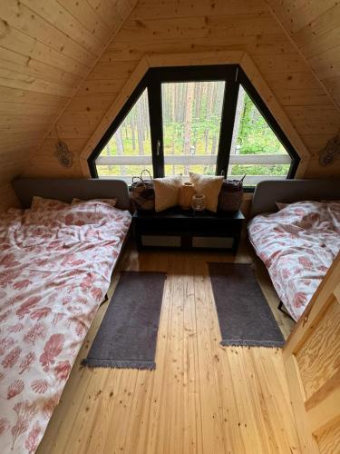 a room with two beds in a attic with windows at Domek rekreacyjny DORAN in Tuczno