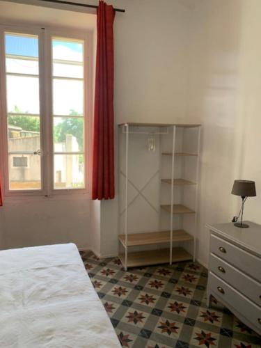 une chambre avec un lit, une commode et une fenêtre dans l'établissement L'Ostal de Terralha avec piscine au centre du village, à Montfrin