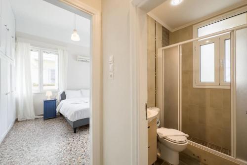a bathroom with a toilet and a bed and a window at Bright & Cozy House near Beach in Athens