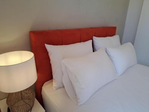 a bedroom with a bed with white pillows and a lamp at Akrogiali in Agios Ioannis Pelio