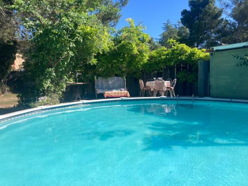 une grande piscine bleue avec une table et des chaises dans l'établissement Villa L Oasis avec piscine, aux Angles (Gard)