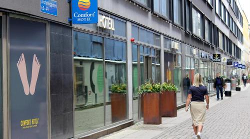 a woman walking down a street in front of a store at Comfort Hotel City in Gothenburg