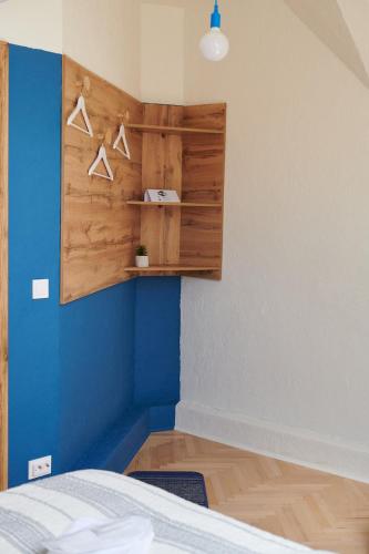 a bedroom with a blue wall with hangers at Lama Hostel in Ivano-Frankivsʼk