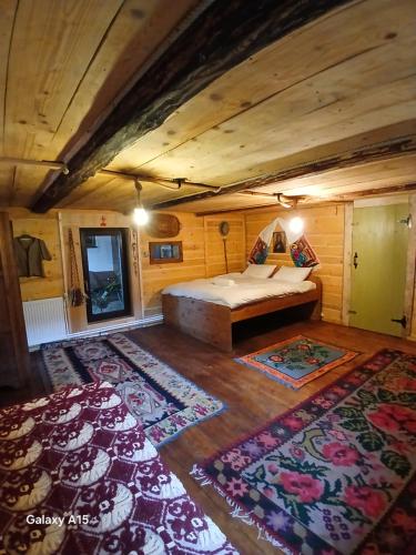 a bedroom with a bed in a room with rugs at Mica fermă veselă in Câmpulung Moldovenesc