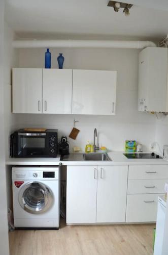 une cuisine avec un lave-linge et un micro-ondes dans l'établissement Charmant 2 pièces à 1 min RER D - 5mn Paris Centre, à Alfortville