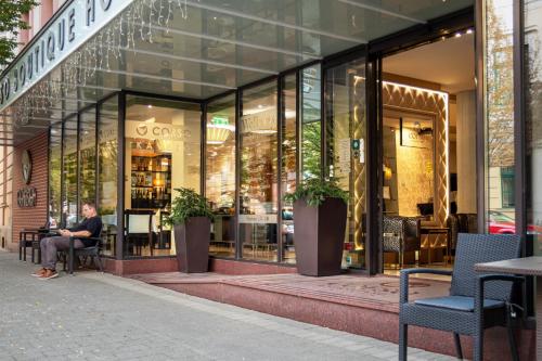 a person sitting in front of a store window at Corso Boutique Hotel in Gyula