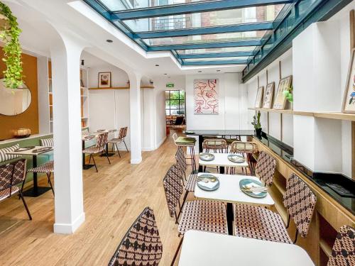 a restaurant with tables and chairs and a skylight at Parici Hôtel Boulogne Billancourt in Boulogne-Billancourt