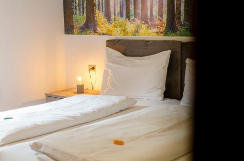 a bed with white sheets and a painting on the wall at Kyrr Smart Mountain Retreat in Moena